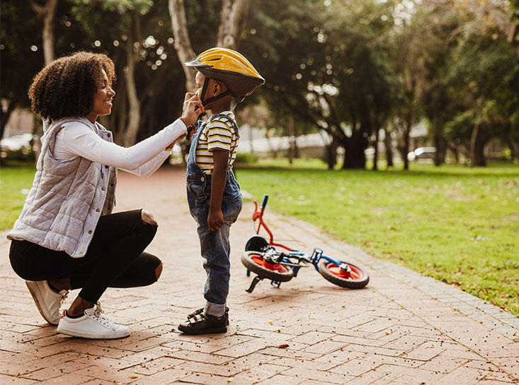 Mother strapping a bike helmet on son