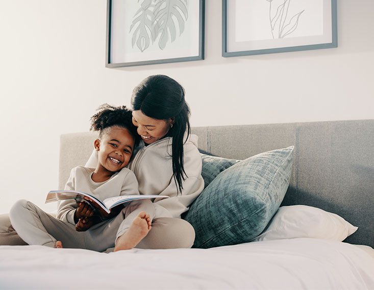 Mother reading a book to her daughter in bed