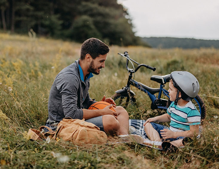 Father sitting in a field playing with young son