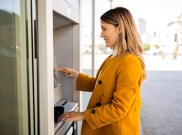 Woman using a First State Bank debit card at ATM