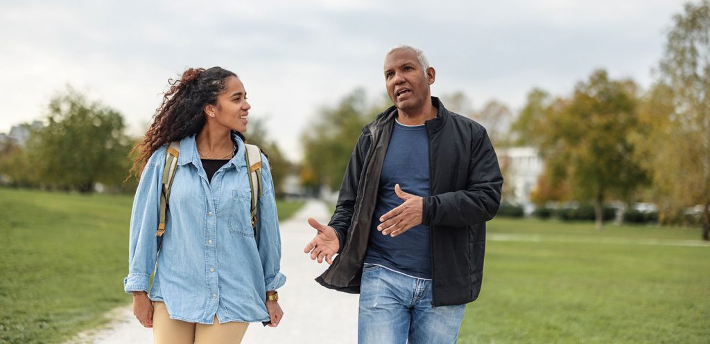 College student and father discuss college budgeting tips while on a walk together.
