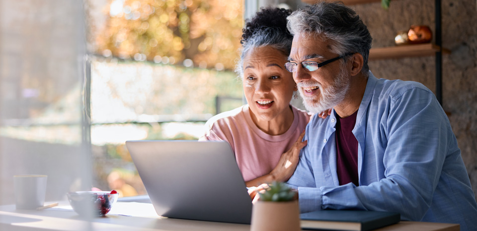 A woman and man excitedly look at a laptop while seeking preapproval on a home loan.